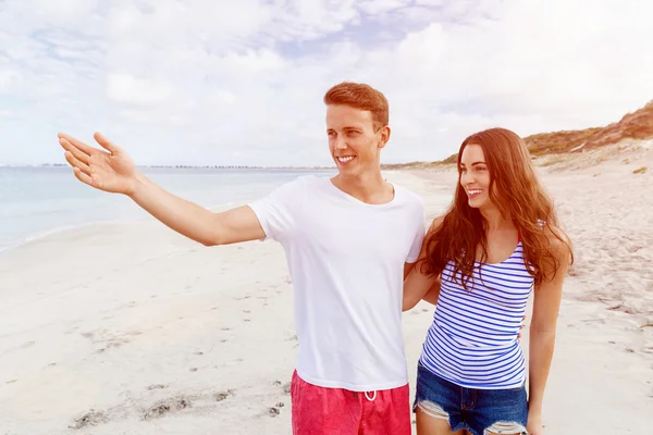 Felice giovane uomo e donna coppia insieme a piedi su una spiaggia — Foto Stock