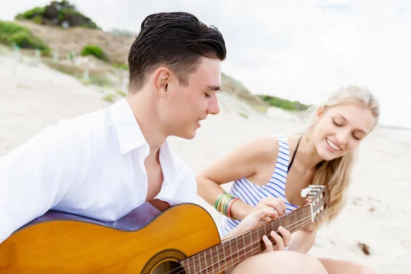 Genç çift aşık sahilde gitar çalmak — Stok fotoğraf
