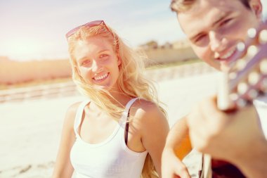 Genç çift aşık sahilde gitar çalmak