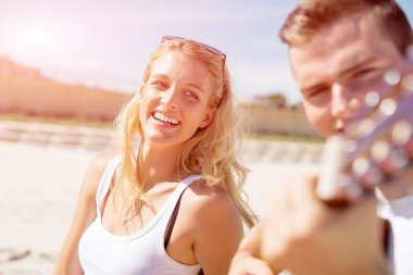 Genç çift aşık sahilde gitar çalmak