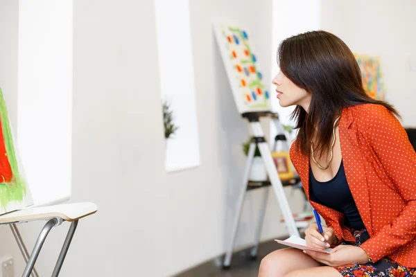 Mujer joven caucásica de pie en la galería de arte frente a las pinturas —  Fotos de Stock