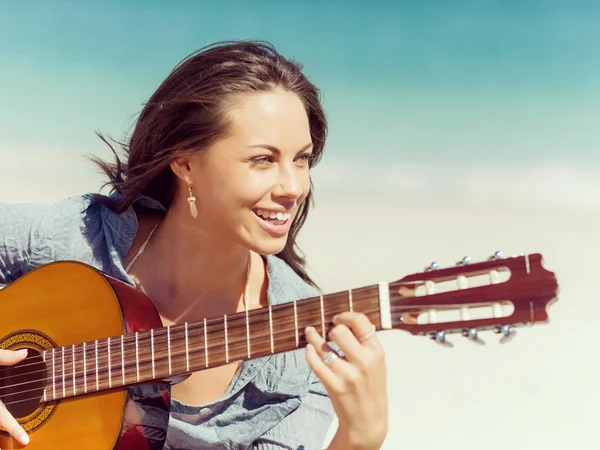 Красивая молодая женщина играет на гитаре на пляже — стоковое фото