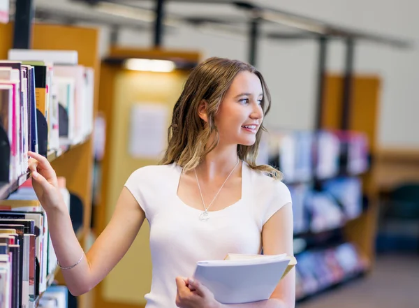 Glückliche Studentin mit Büchern in der Bibliothek — Stockfoto