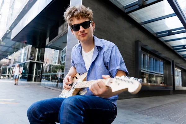 Joven músico con guitarra en la ciudad — Foto de Stock