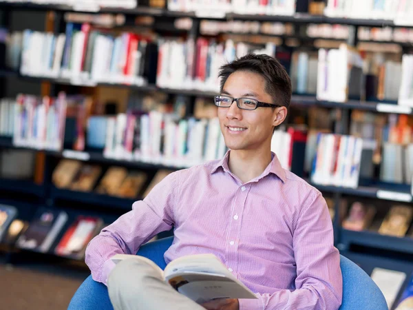 Glücklicher männlicher Student mit Büchern in der Bibliothek — Stockfoto