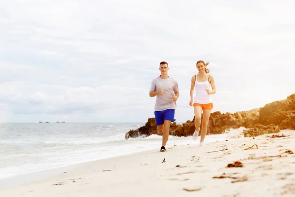 Des coureurs. Jeune couple courant sur la plage — Photo