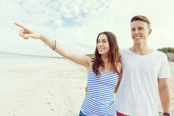 Gelukkige jonge man en vrouw paar samen wandelen op een strand — Stockfoto