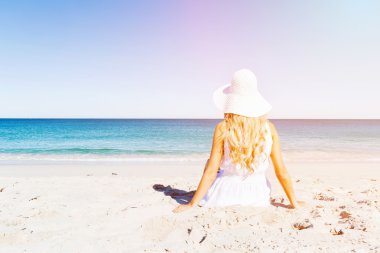 Genç bir kadın sahilde dinleniyor.