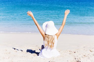 Genç bir kadın sahilde dinleniyor.