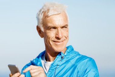 Erkek runner mobil akıllı telefonunu açık havada duran ile