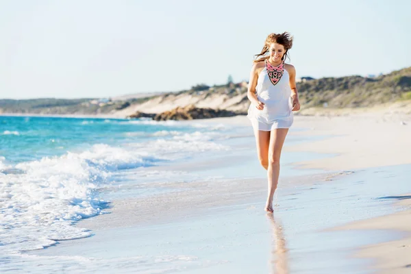 Junge Frau läuft am Strand entlang — Stockfoto