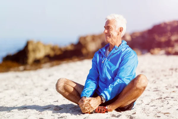 Homem de roupas esportivas sentado na praia — Fotografia de Stock
