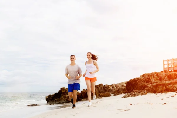 Des coureurs. Jeune couple courant sur la plage — Photo