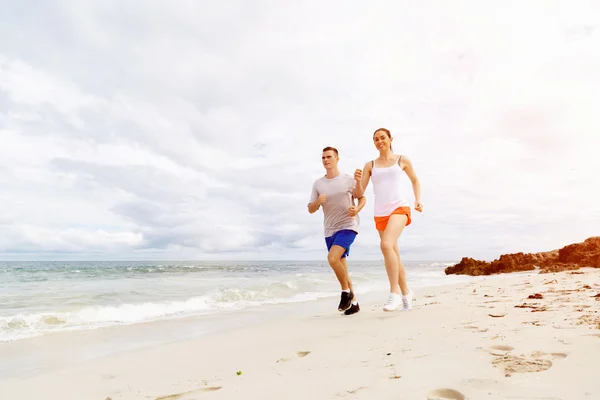 Des coureurs. Jeune couple courant sur la plage — Photo