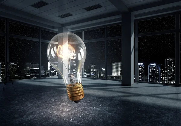 Glowing light bulb in modern office — Stock Photo, Image