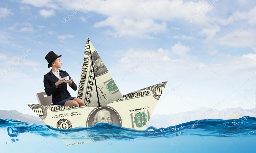Businesswoman in boat made of dollar banknote