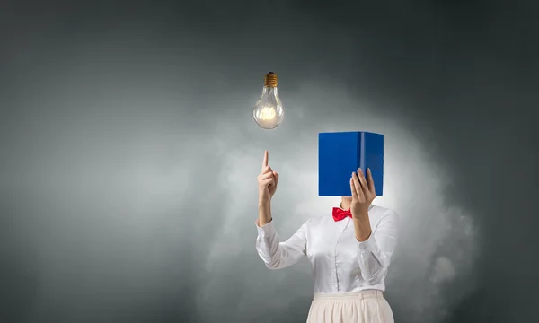 Woman hiding face behind book — Stock Photo, Image