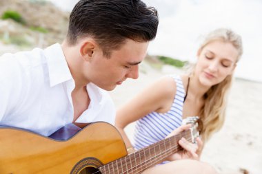 Genç çift aşık sahilde gitar çalmak