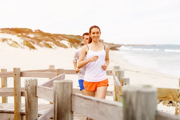 Des coureurs. Jeune couple courant sur la plage — Photo