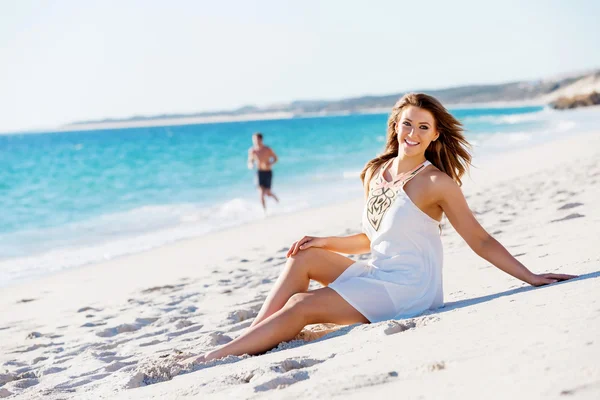 Jonge vrouw zittend op het strand — Stockfoto