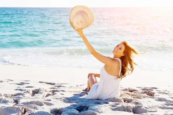 Jonge vrouw zittend op het strand — Stockfoto