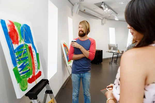 Jóvenes de pie en una galería contemplando obras de arte —  Fotos de Stock