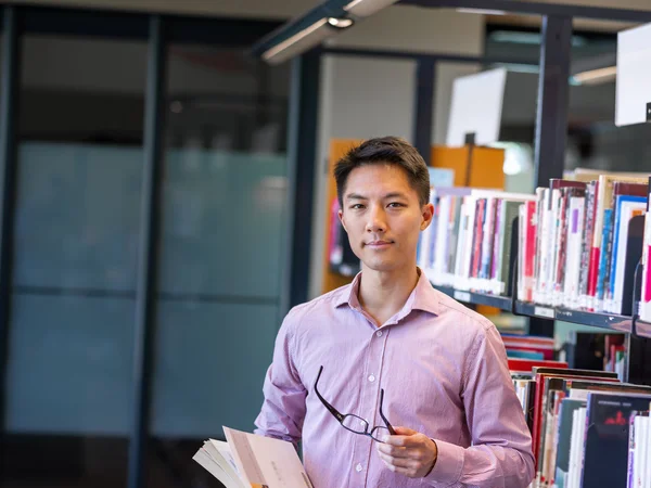 Szczęśliwy studentowi trzymania książek w bibliotece — Zdjęcie stockowe