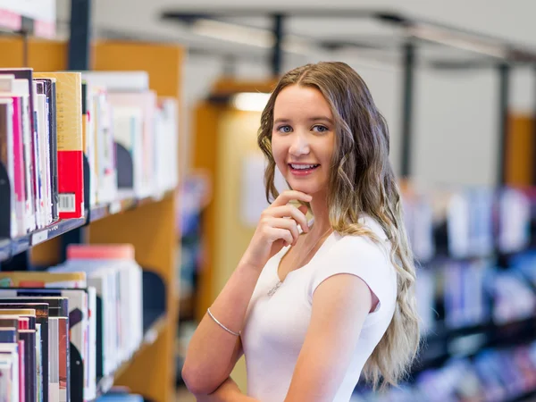 Gelukkig vrouwelijke student oppakken van boeken in de bibliotheek — Stockfoto