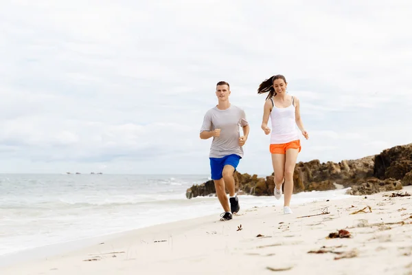 Des coureurs. Jeune couple courant sur la plage — Photo