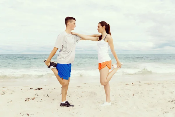 Corridori. Giovane coppia esercizio e poppa sulla spiaggia — Foto Stock