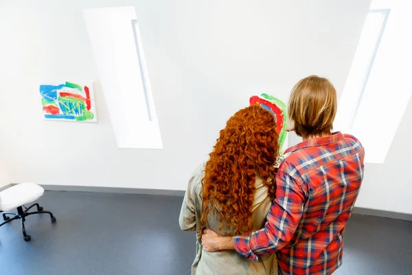 Jeune couple caucasien debout dans une galerie et contemplant des œuvres d'art — Photo