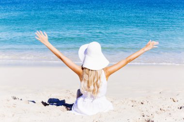 Genç bir kadın sahilde dinleniyor.