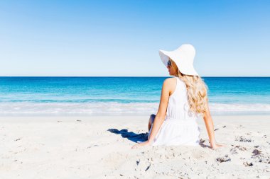 Genç bir kadın sahilde dinleniyor.