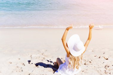 Genç bir kadın sahilde dinleniyor.