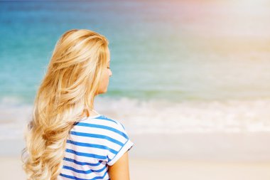 Genç bir kadın sahilde dinleniyor.