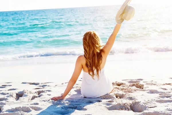 Jonge vrouw zittend op het strand — Stockfoto