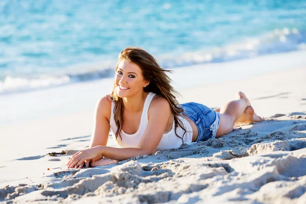 Genç bir kadın sahilde dinleniyor.