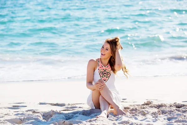 Jonge vrouw zittend op het strand — Stockfoto