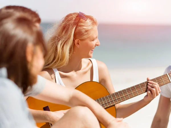 Schöne junge Frau spielt Gitarre am Strand — Stockfoto