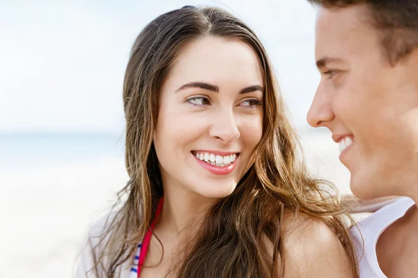 Romantische jonge paar zittend op het strand — Stockfoto