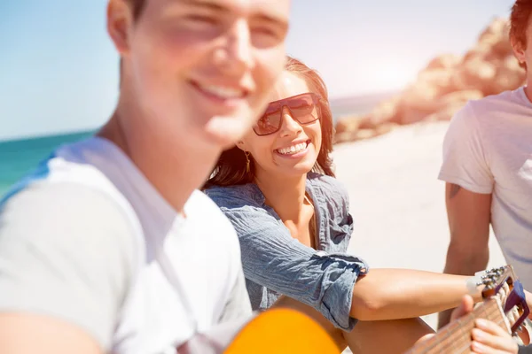 Jovens bonitos com guitarra na praia — Fotografia de Stock