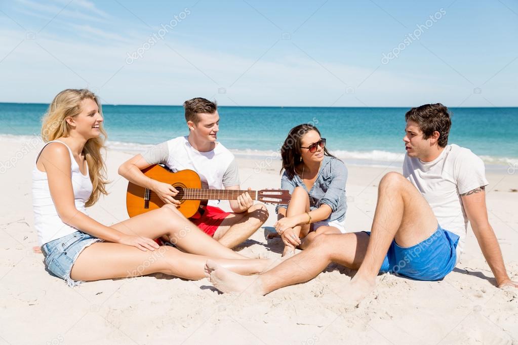 Beautiful young people with guitar on beach