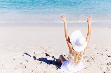 Genç bir kadın sahilde dinleniyor.