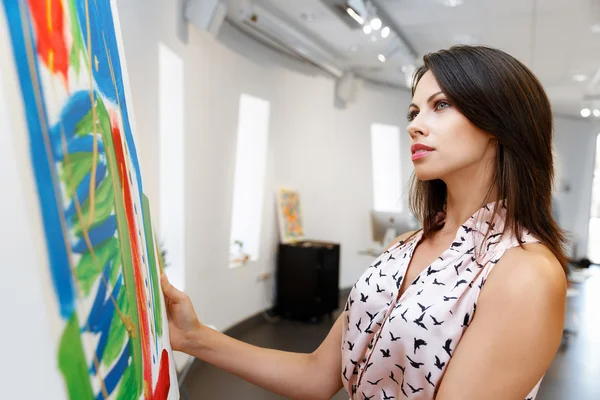 Jonge Kaukasische vrouw permanent in kunst galerij voor schilderijen — Stockfoto