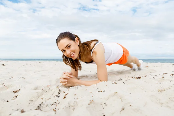 Mujer joven entrenando en la playa afuera — Foto de Stock