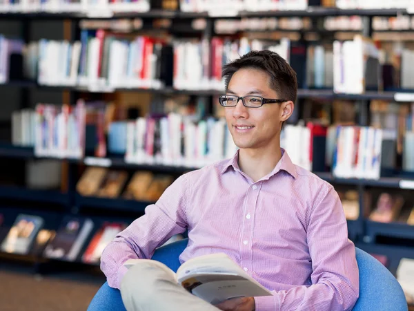 Glücklicher männlicher Student mit Büchern in der Bibliothek — Stockfoto