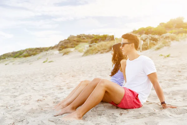 Romantiska unga paret sitter på stranden — Stockfoto