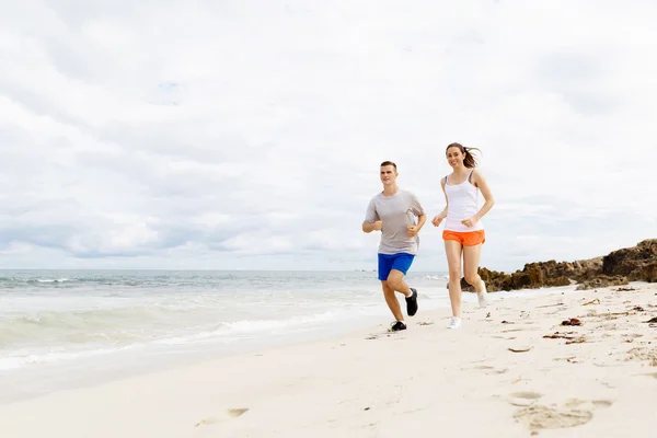 Des coureurs. Jeune couple courant sur la plage — Photo