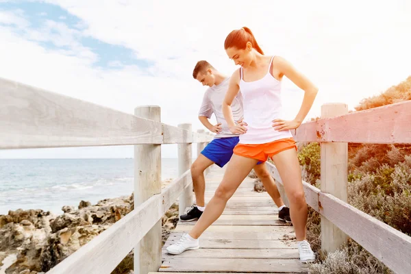 Des coureurs. Jeune couple exerçant et stertching sur la plage — Photo