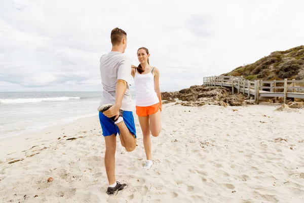 Lopers. Jong koppel uit te oefenen en stertching op strand — Stockfoto